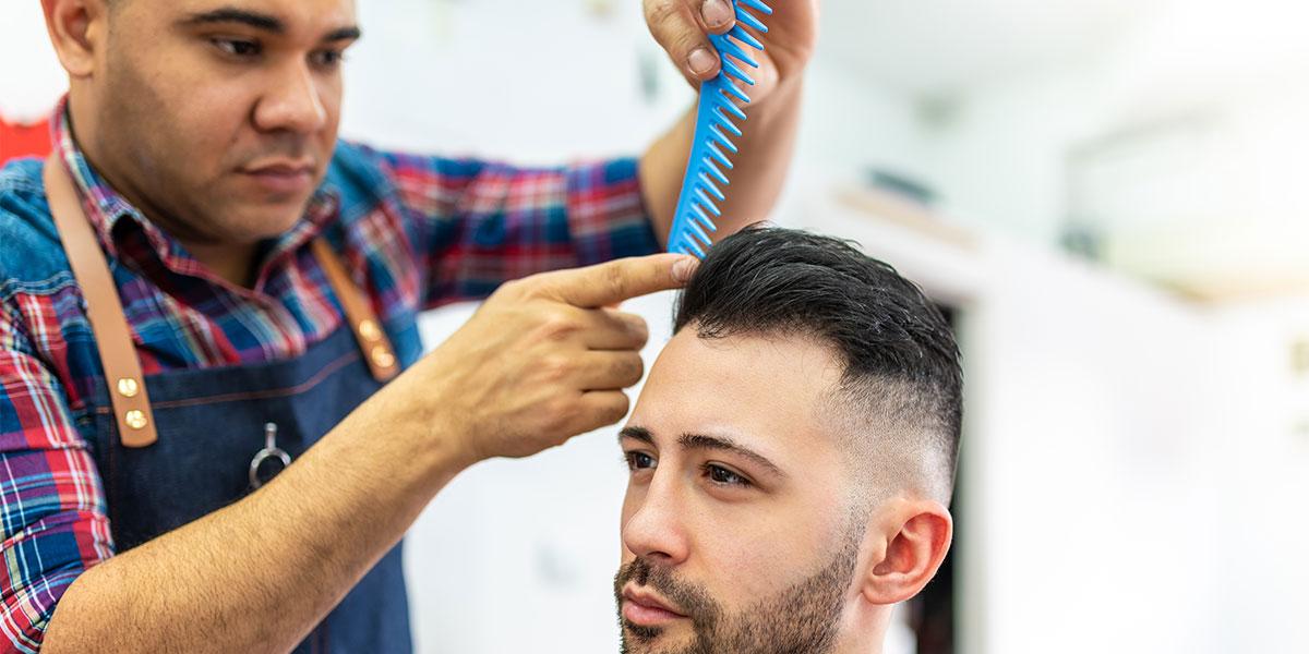 A barber combs a mans hair.